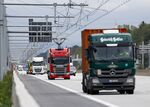 A Scania AB R450 cargo e-truck powered by overhead electrical power lines drives alongside other non-electric trucks on the A5 autobahn between Frankfurt and Darmstadt, Germany.