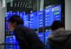 Two men stand in front of a screen displaying stock indices at the Tokyo Stock Exchange (TSE), operated by Japan Exchange Group Inc. (JPX), in Tokyo, Japan, on Friday, Feb. 9, 2018. The Topix index headed for its worst week in two years following a meltdown in U.S. equities amid concern rising interest rates will damp economic growth.