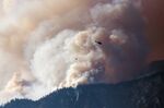 A helicopter prepares to make a water drop as smoke billows along the Fraser River Valley near Lytton, British Columbia, on&nbsp;July 2.