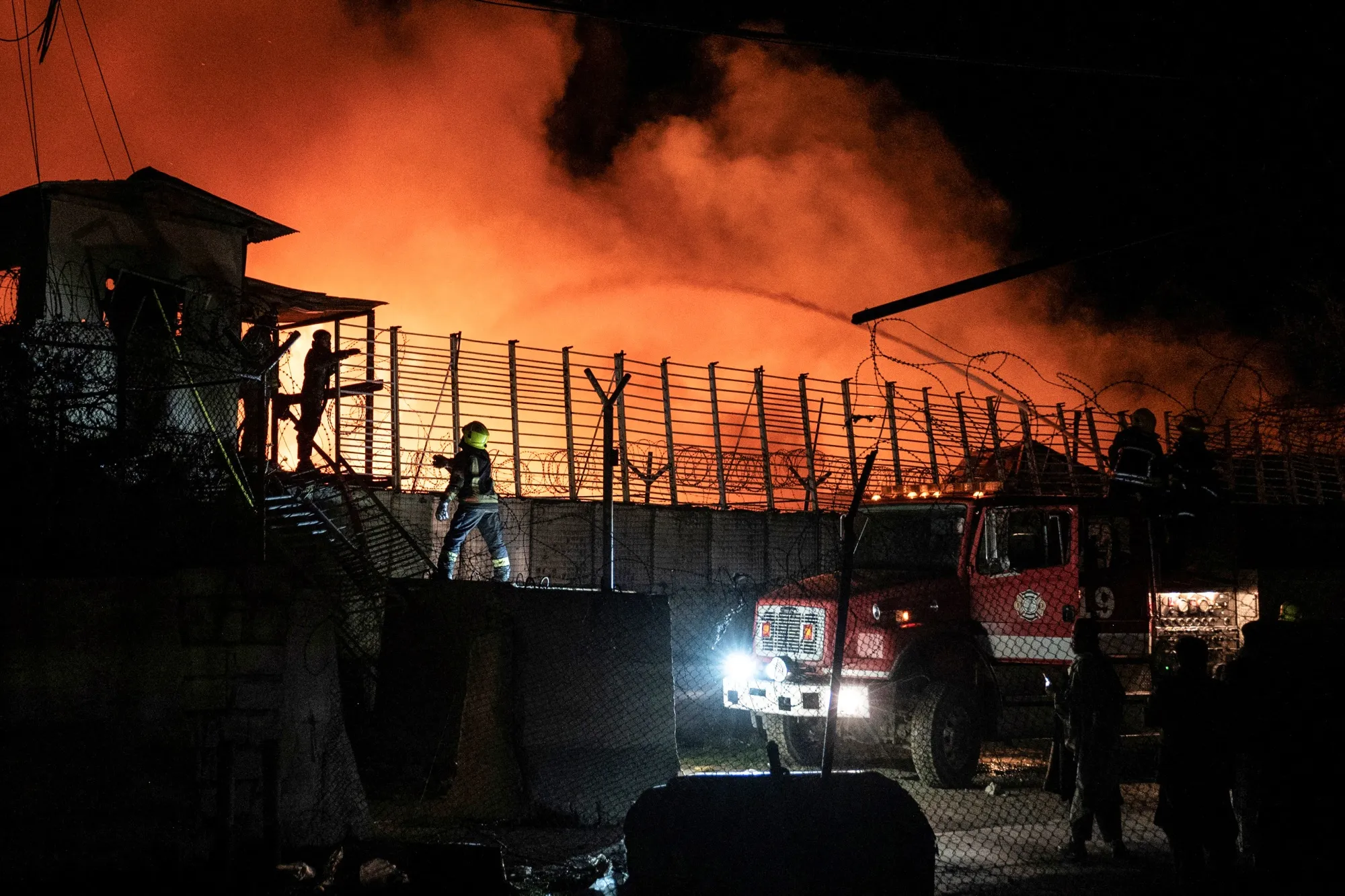 Afghan firefighters and Taliban security personnel work to extinguish a fire at the Secondary Rehabilitation Services Centre in Kabul on March 16.