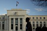A pedestrian walks past the Marriner S. Eccles Federal Reserve building in Washington, D.C., U.S., on Tuesday, Dec. 15, 2015. E