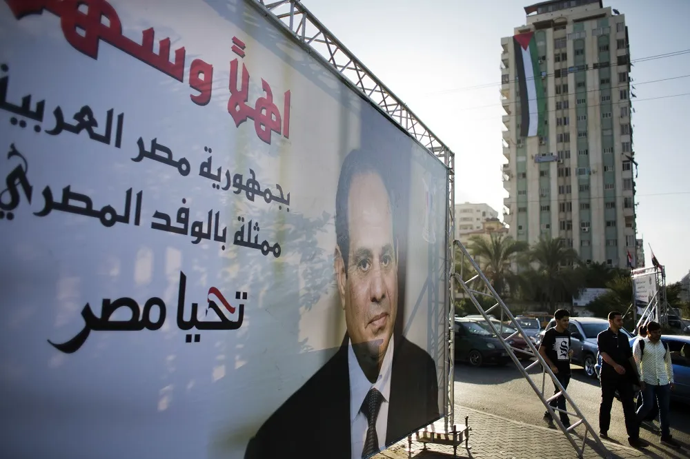 Palestinians pass by a staged poster of Egyptian president Abdel-Fattah El-Sisi t in Gaza City, Tuesday, Oct. 3, 2017.
