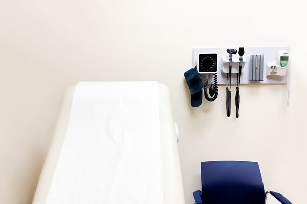 access to medical care: wall-mounted medical diagnostic equipment beside standard patient examination chair