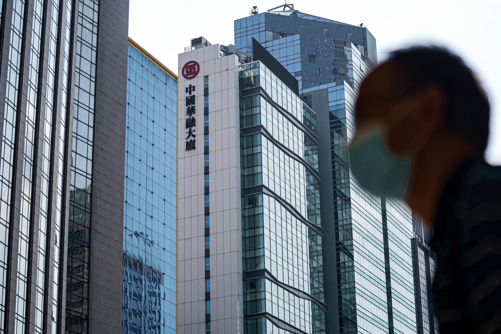 A pedestrian walks past the China Huarong Tower in Hong Kong.