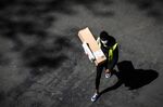 A delivery man wearing a protective mask carries an Amazon box in Paris on April 15.