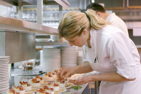 A pastry chef puts some minty garnish on a panna cotta.