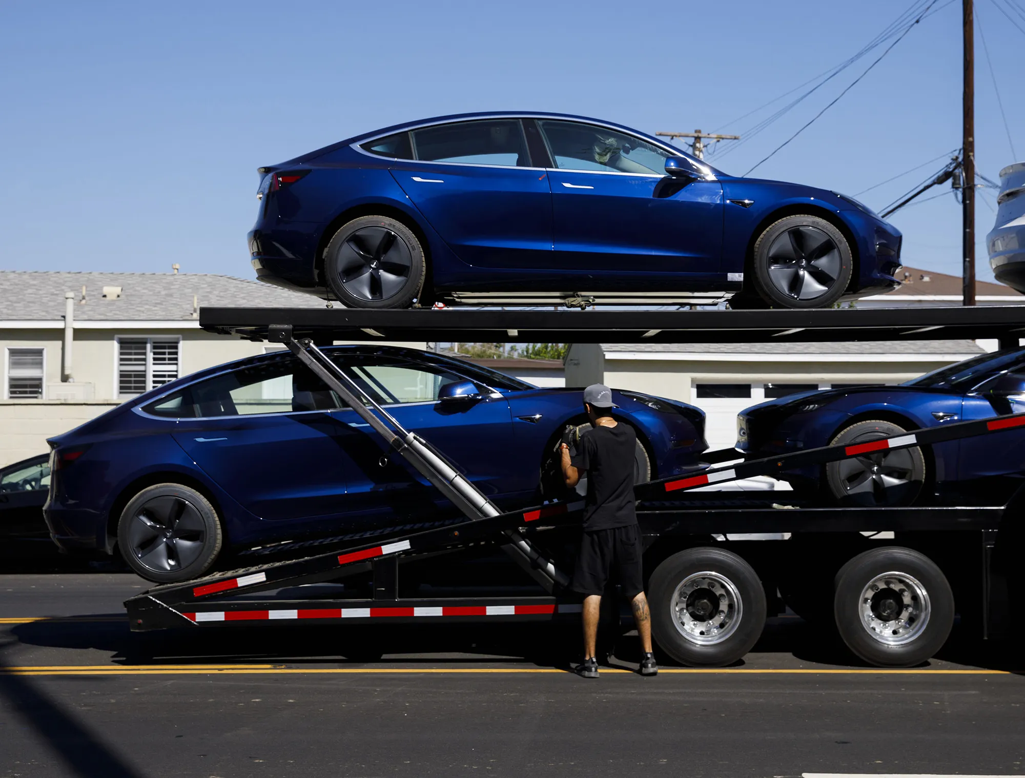 Workers unload Tesla Model 3 electric vehicles outside the company's delivery center in Marina Del Rey, California.