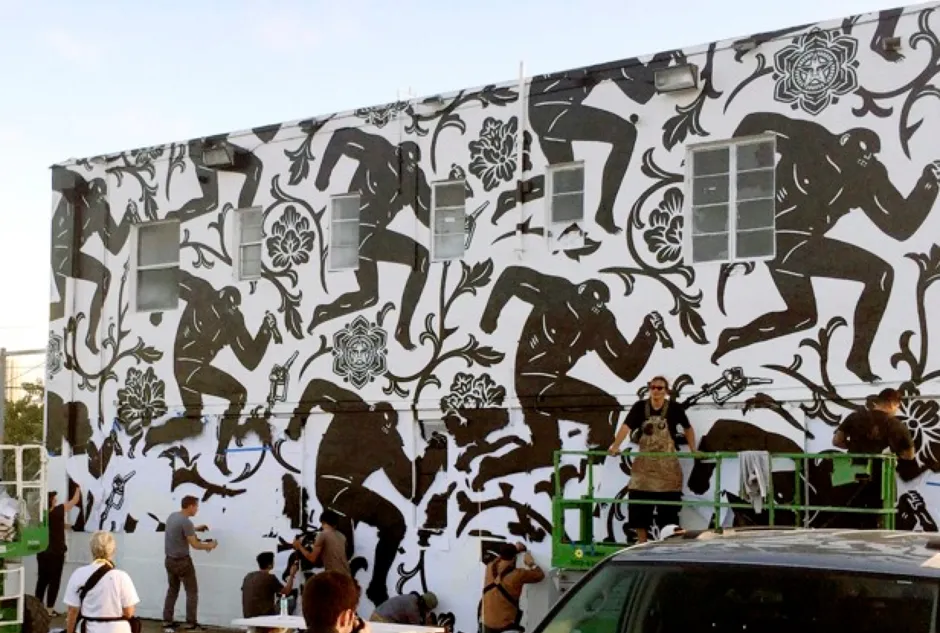 Shepard Fairey (lower left, gray shirt) puts the finishing touches on the mural titled "Power and Glory" in the Wynwood section of Miami in 2014.