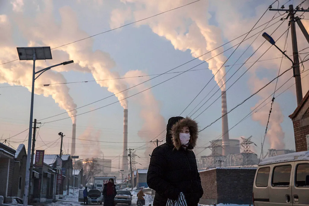 Smoke billows from stacks as a&nbsp;woman wears a&nbsp;mask&nbsp;near a coal fired power plant in Shanxi, China.&nbsp;