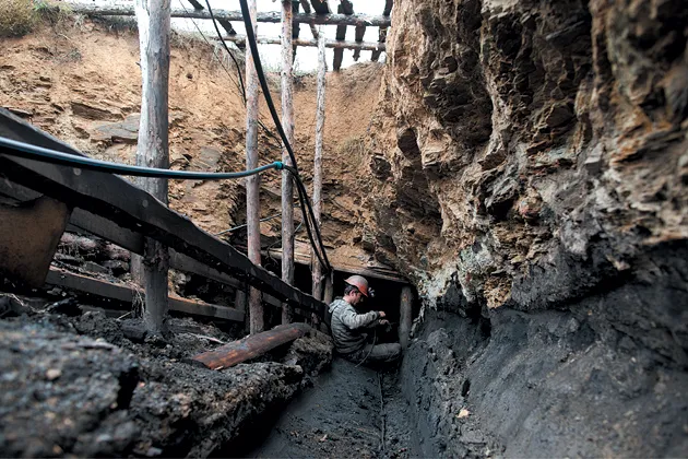 A worker repairs a cable at the entrance of an illegal mine near Davydovka