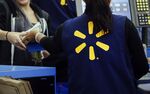 Employees assist shoppers at the check out counter of a Wal-Mart Stores Inc. location in Los Angeles, California.
