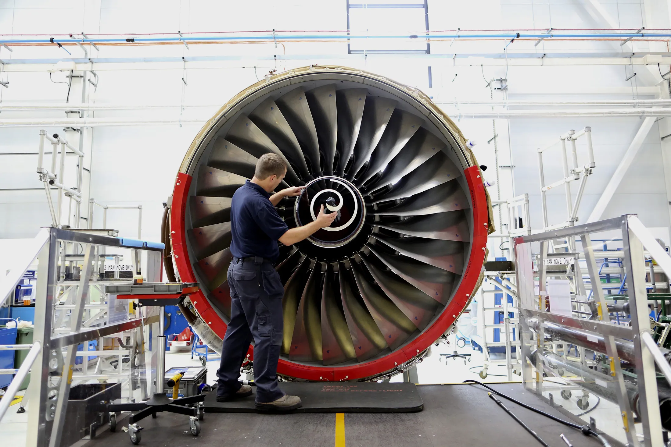 An employee fits the nose cone to a Trent 700 aircraft engine on the production line at the Rolls-Royce Holdings Plc factory in Derby, U.K., on Wednesday, Aug. 19, 2015. Rolls-Royce's XWB engine developed for the Airbus A350 should bring in twice the cash flow than the existing Trent 700 model on the Airbus A330, Chief Executive Warren East said in July.

