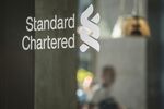 The Standard Chartered Plc logo is displayed on a glass panel at a bank branch