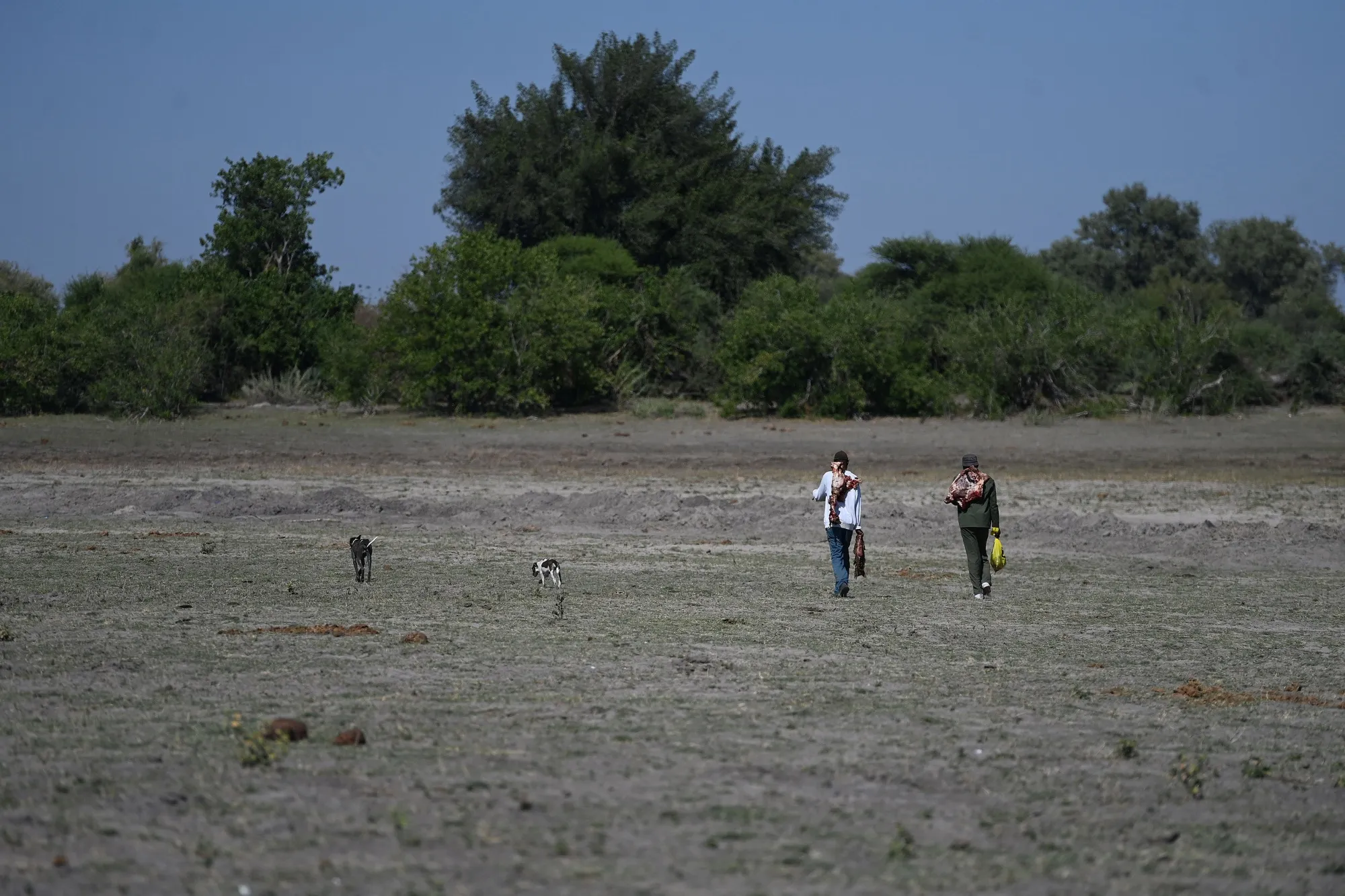 People walk through a dried channel near Nxaraga village in the Okavango Delta, in Botswana.