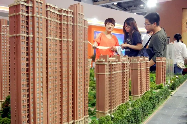 Chinese home buyers look at models of a residential property project during a real estate fair in Suzhou