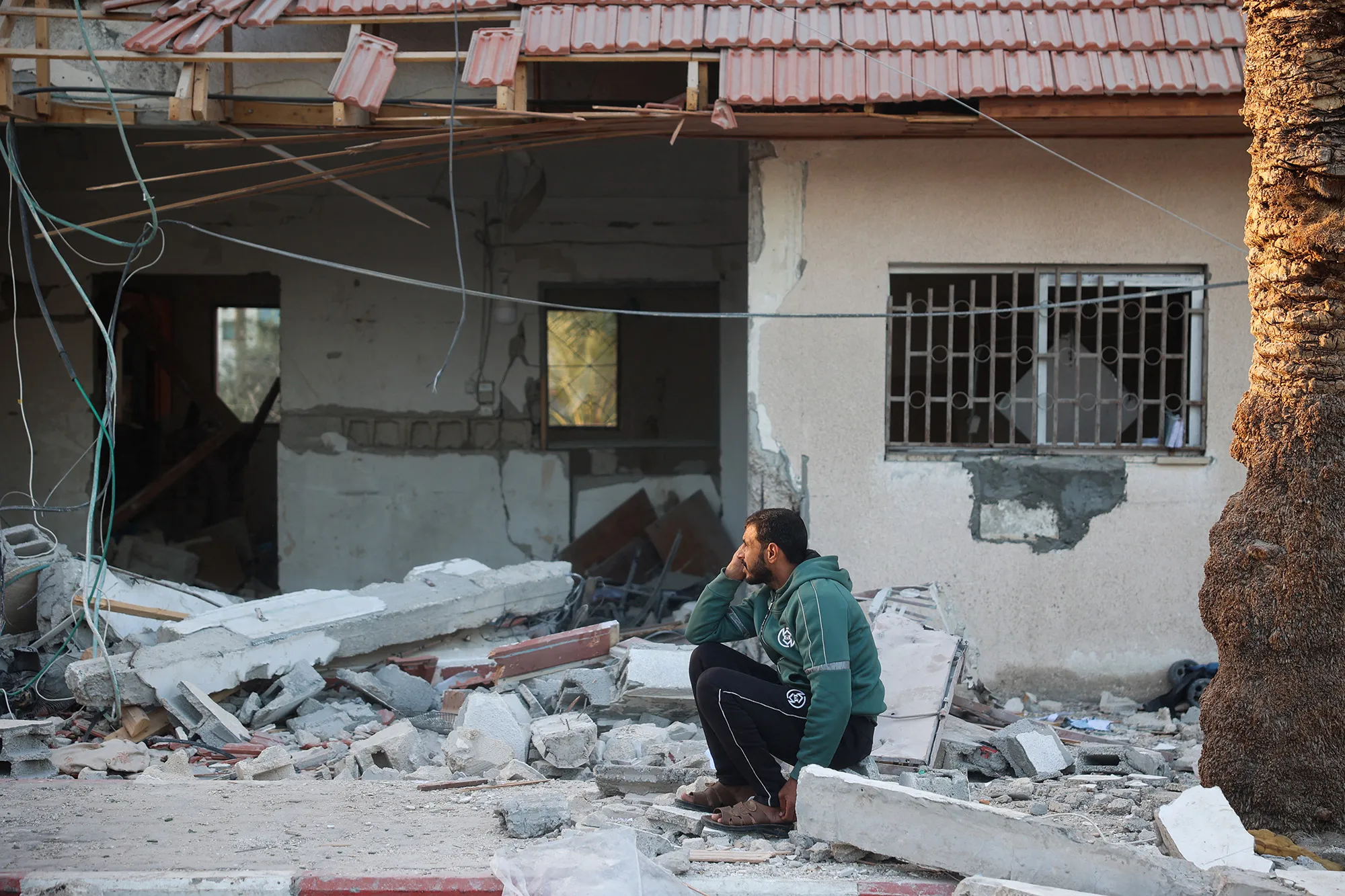 A resident sits by building rubble following an Israeli strike in Deir el-Balah, Gaza, on Dec. 14.