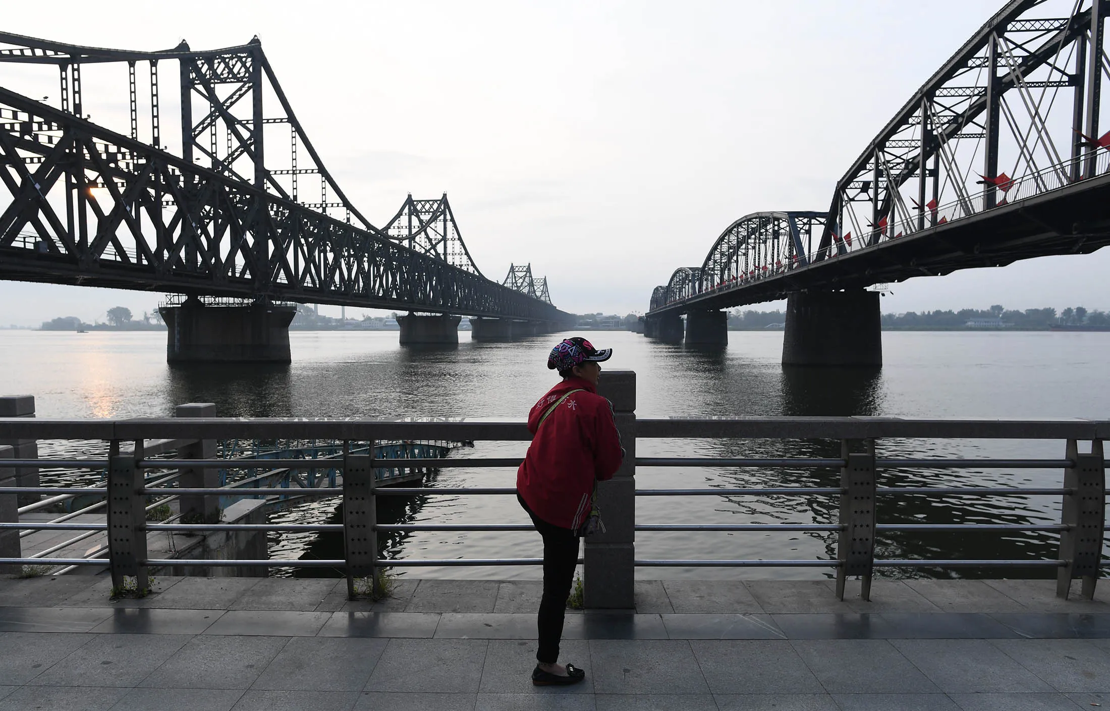 A woman stretches below the China-North Korea Friendship Bridge and the Broken Bridge in Dandong, China.
