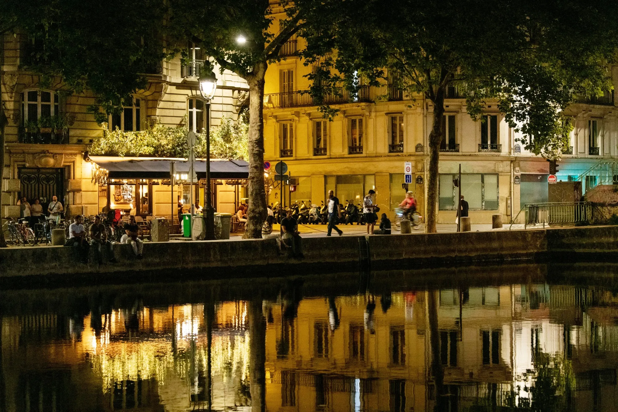 Buildings lit by street lights are reflected in the Canal Saint-Martin in Paris, France.