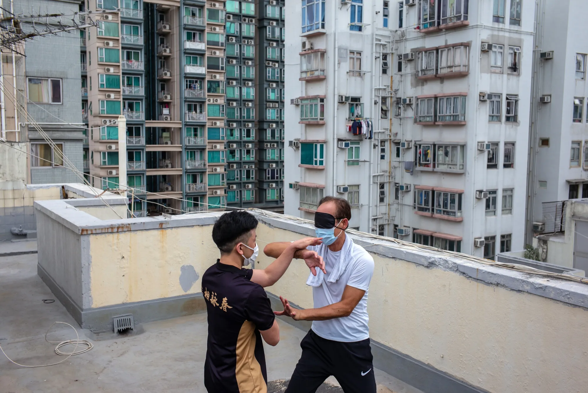 Lam Shu-shing, wearing a protective mask and a blindfold, practices with a student on the rooftop of a building in Hong Kong.