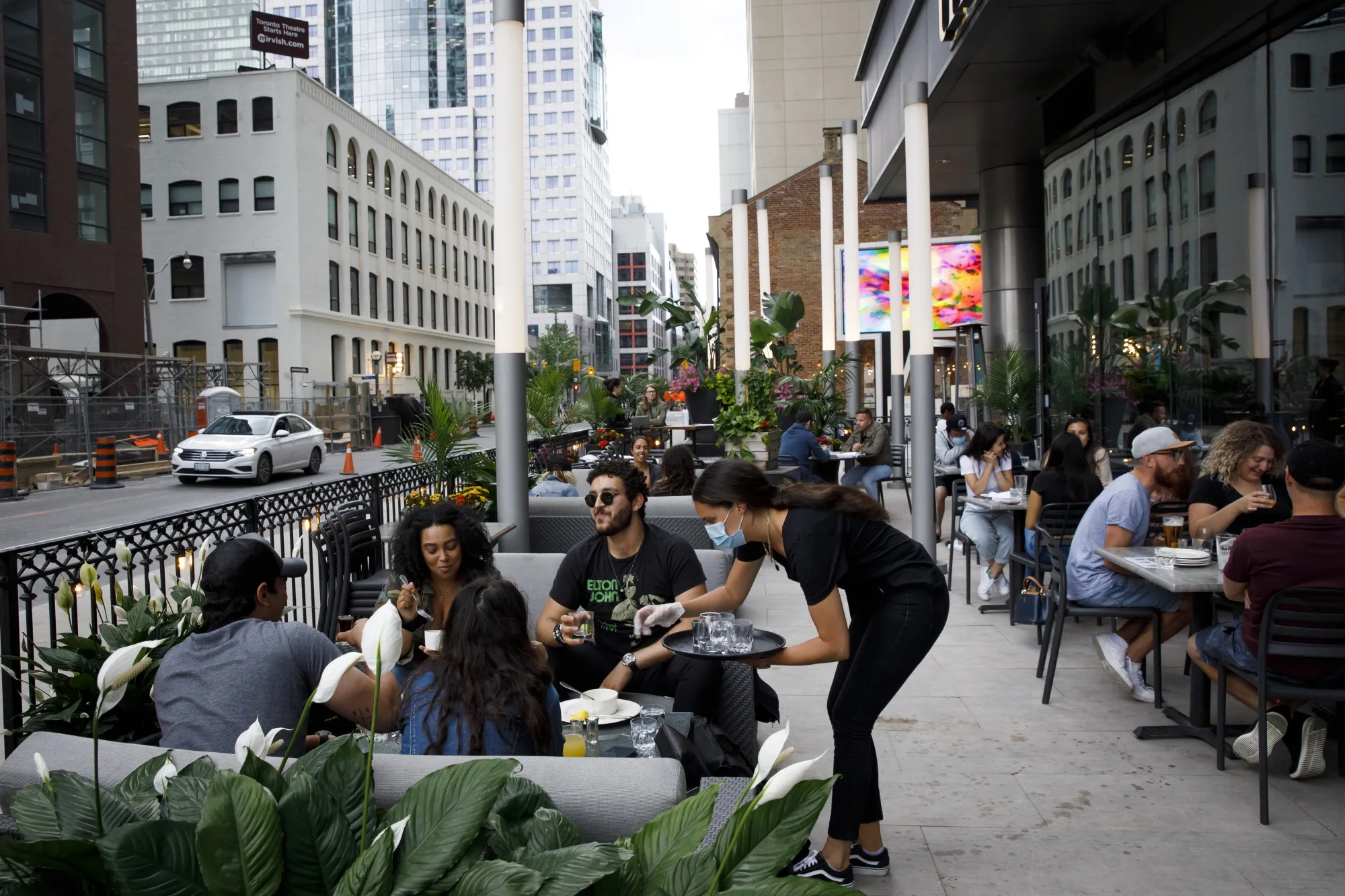 A server wearing a protective mask collects glasses at a patio in Toronto, Ontario, Canada, on June 24. Canada's largest city has reopened restaurant patios, shops and swimming pools after officials determined that the Covid-19 virus is under control.