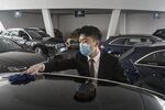 An employee wearing a protective mask wipes a vehicle on display inside a&nbsp;dealership in Wuhan, China.