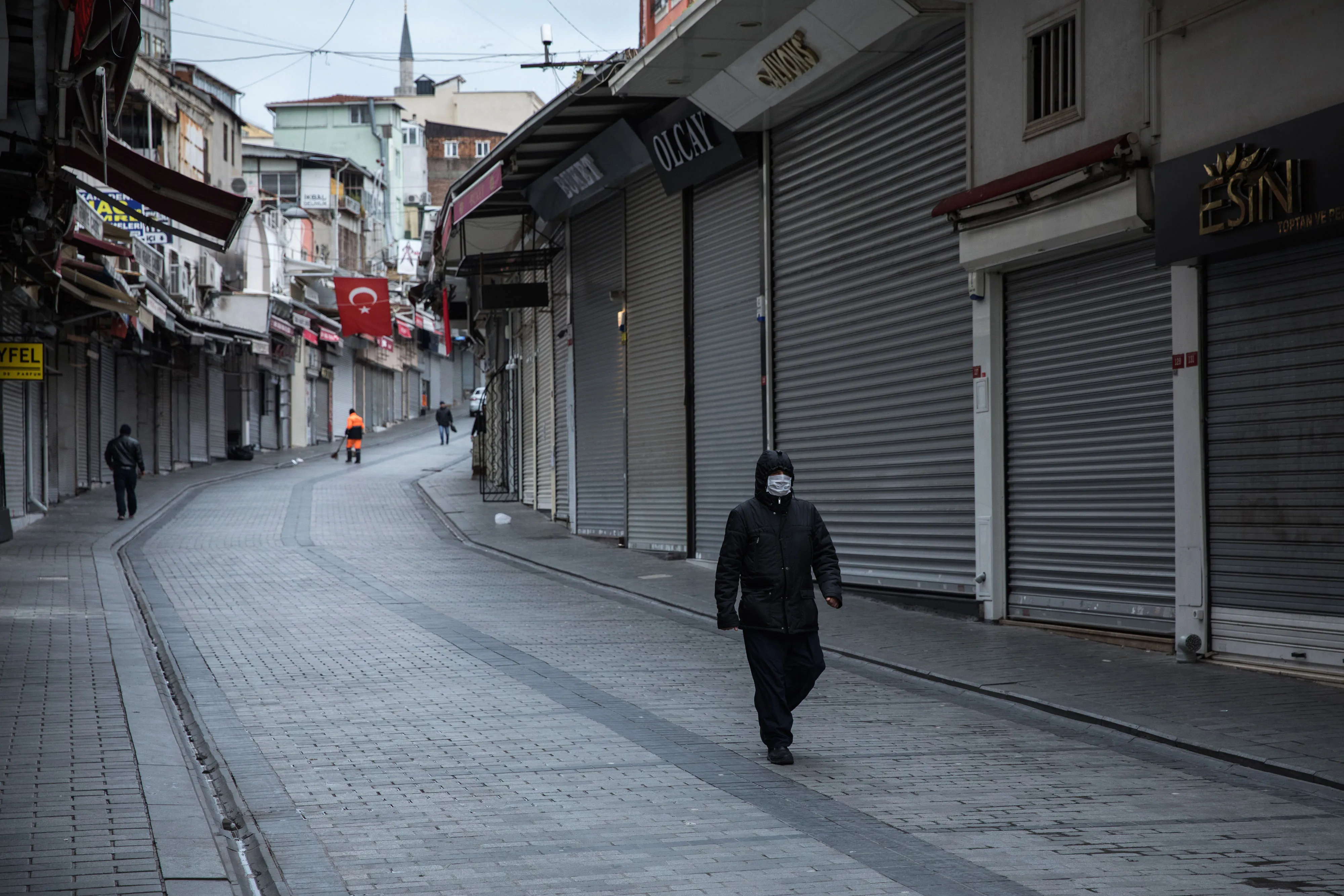 A pedestrian wearing a protective face mask passes retail stores closed to prevent the spread of coronavirus in Istanbul on March 25.