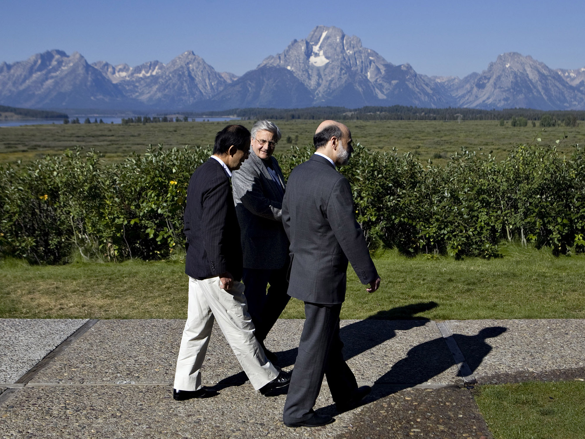 Ben S. Bernanke, right, walks with ECB President Jean-Claude Trichet, center, and Bank of Japan Governor Masaaki Shirakawa outside the Jackson Lake Lodge during a coffee break at the Jackson Hole Economic Symposium in Moran, Wyoming on Aug. 21, 2009.