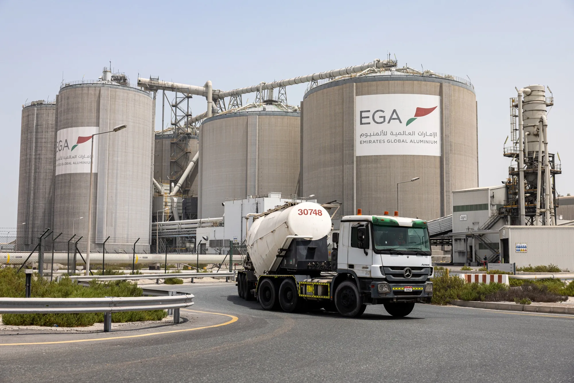A truck passes silos at the Emirates Global Aluminium PJSC Al Taweelah plant in Abu Dhabi.