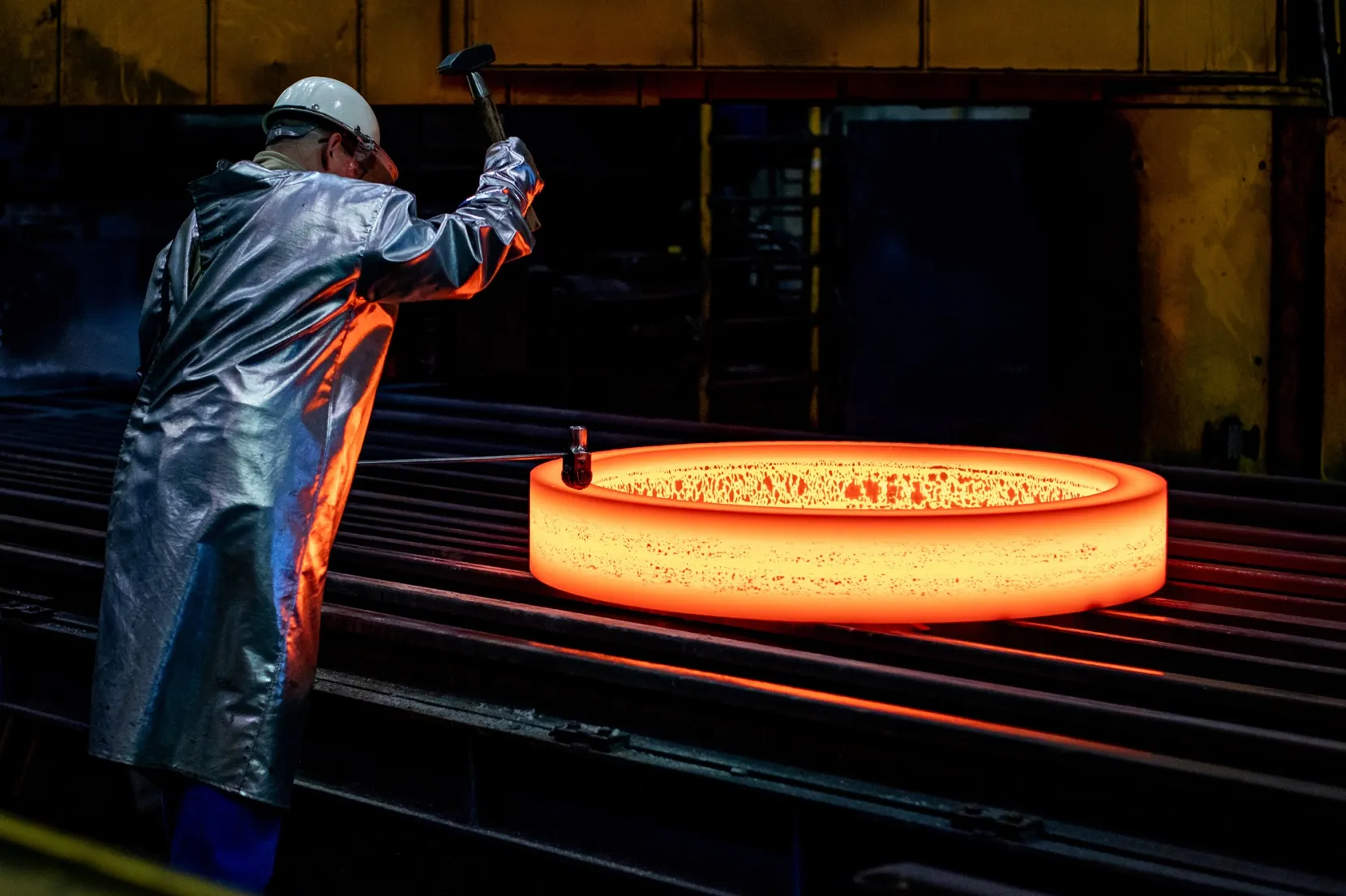 An employee stamps a glowing blank at the ThyssenKrupp Rothe Erde plant in Dortmund, Germany.