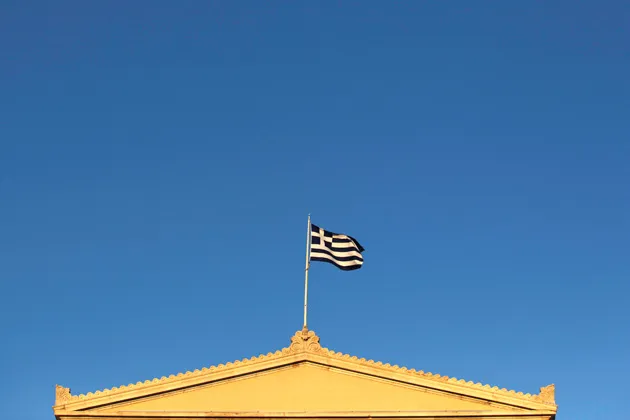 The Greek national flag flies above Parliament in Athens