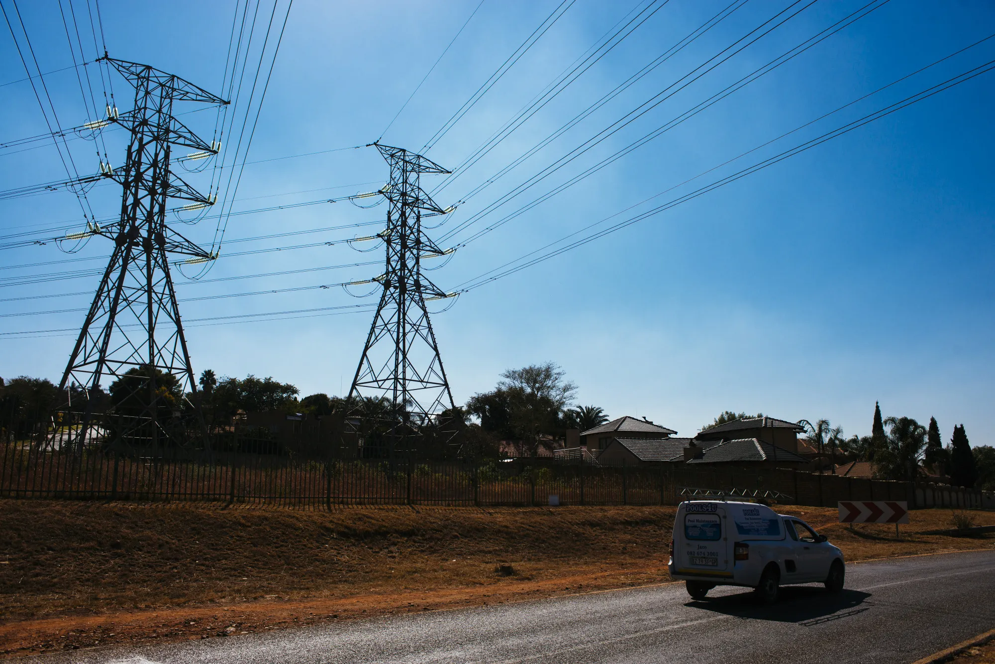 A vehicle drives under electrical power lines hanging from&nbsp;pylons in Pretoria.