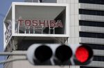 Signage for Toshiba Corp. displayed at the company's headquarters while a red traffic light is illuminated in Tokyo, Japan, on Wednesday, April 7, 2021.
