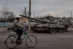 A man rides his bike past a destroyed Russian tank in Trostyanets, Ukraine.&nbsp;