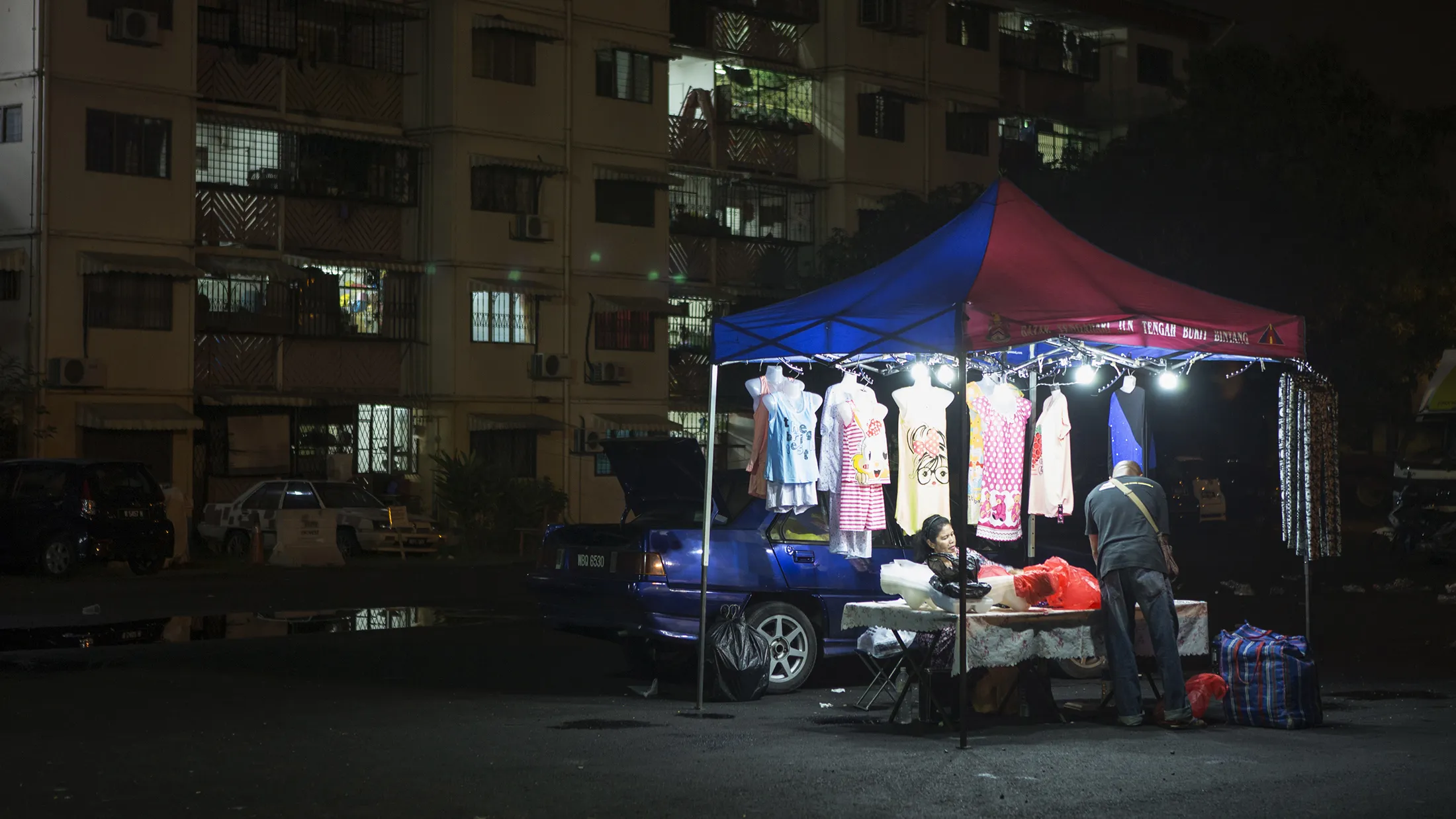 A vendor arranges merchandise at a clothing stall at Bandar Baru Sentul night market in Kuala Lumpur.
