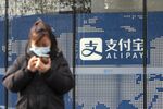 A pedestrian uses a smartphone in front of an Alipay sign outside an Ant Group Co. office building in Shanghai, China, on Thursday, Dec. 24, 2020.