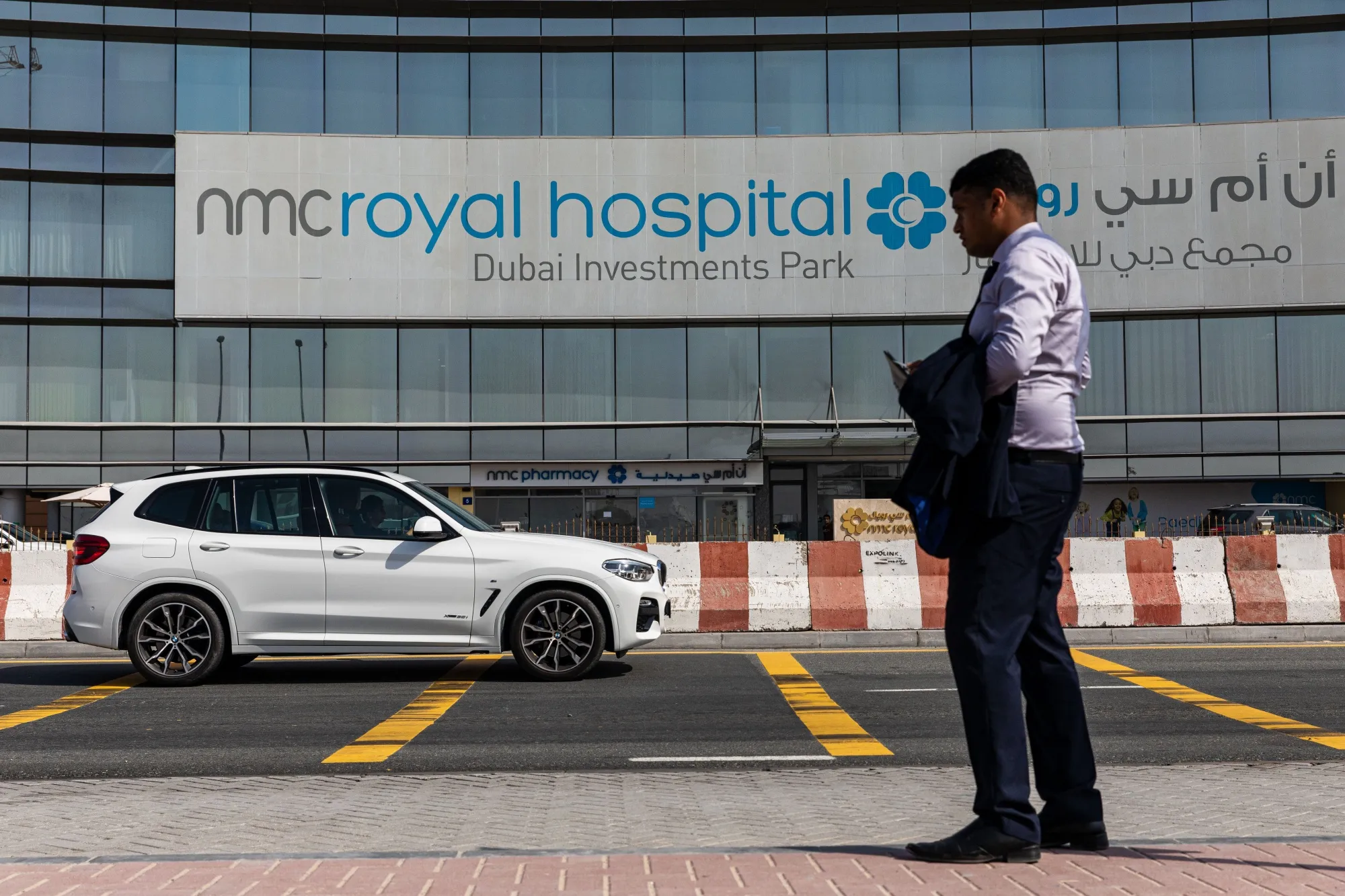 A pedestrian waits outside the entrance to the NMC Royal Hospital in Dubai.