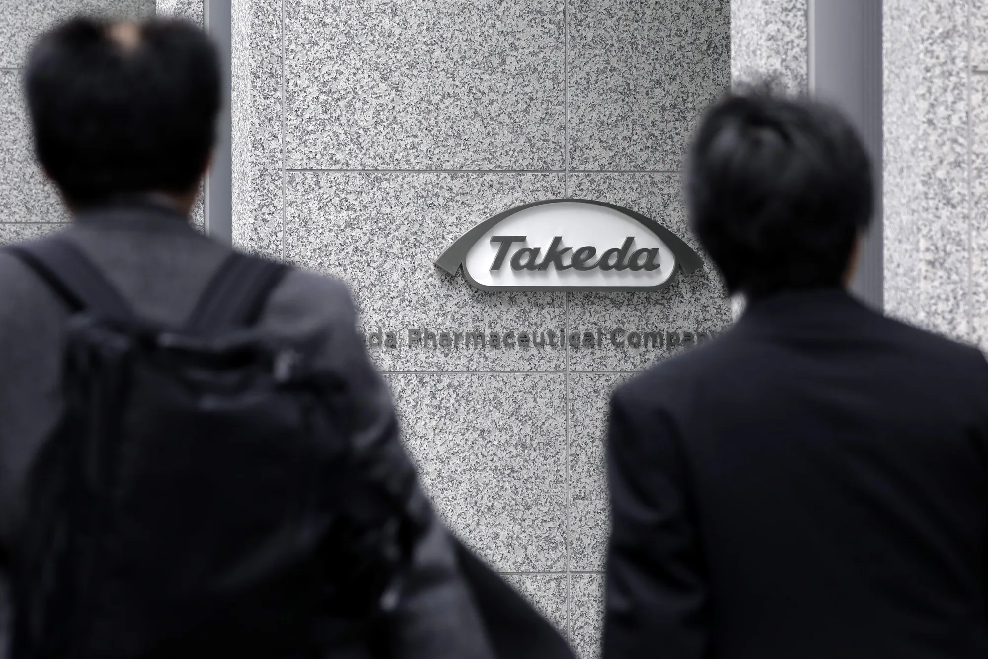 Pedestrians walk past the Takeda Pharmaceutical Co. global headquarters in Tokyo.
