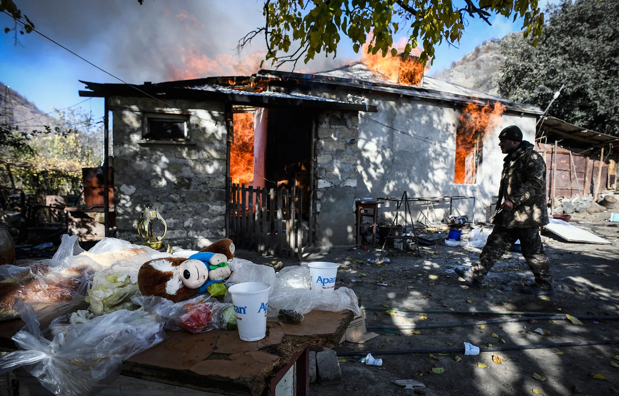 A man walks past a burning house in 2020 during the military conflict between Armenia and Azerbaijan over the breakaway region of Nagorno-Karabakh.