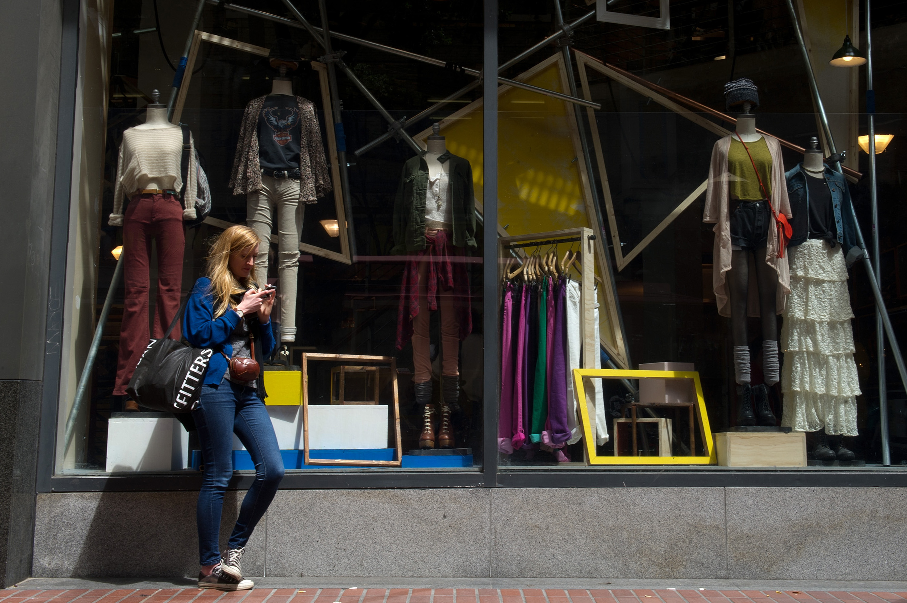 A woman checks her cell phone outside an Urban Outfitters store in San Francisco on Aug. 11, 2011.
