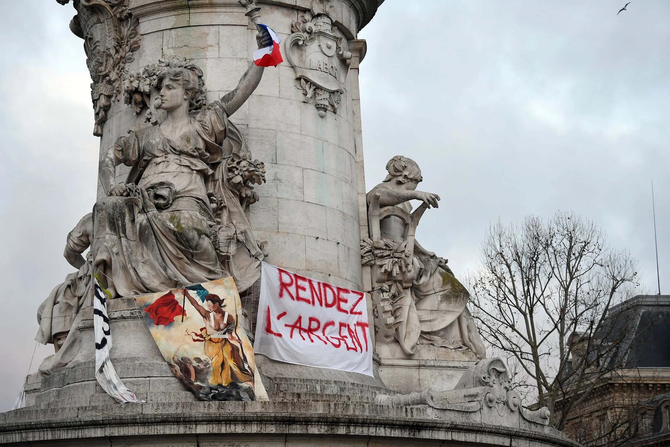 A statue on place de la Republique&nbsp;shows a sign reading "Give the money back" a day after a "yellow vest" demonstrations, Dec. 9.
