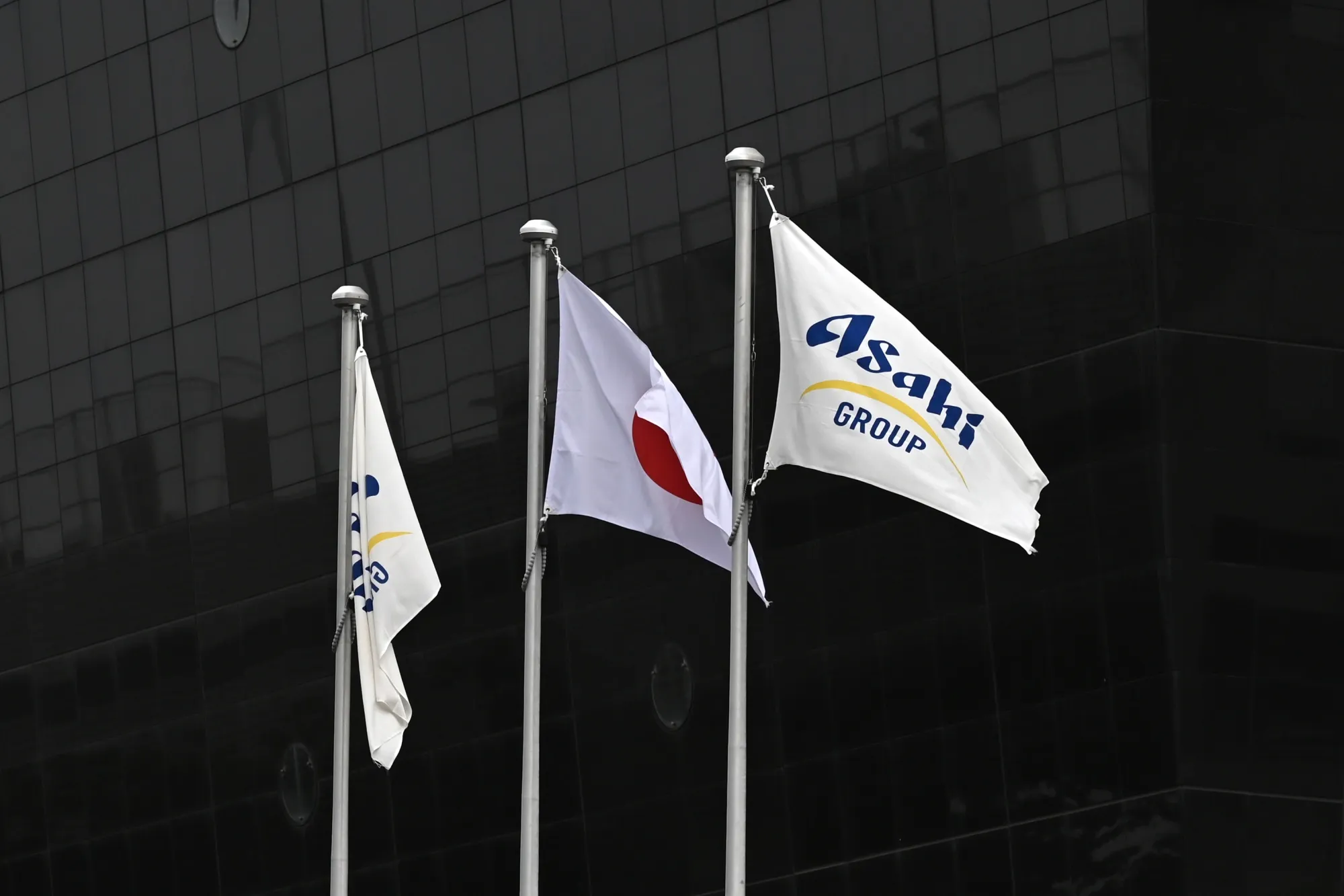 東京のアサヒグループホールディングス本社前に掲げられた日本の国旗と同社の旗（2025年10月3日）