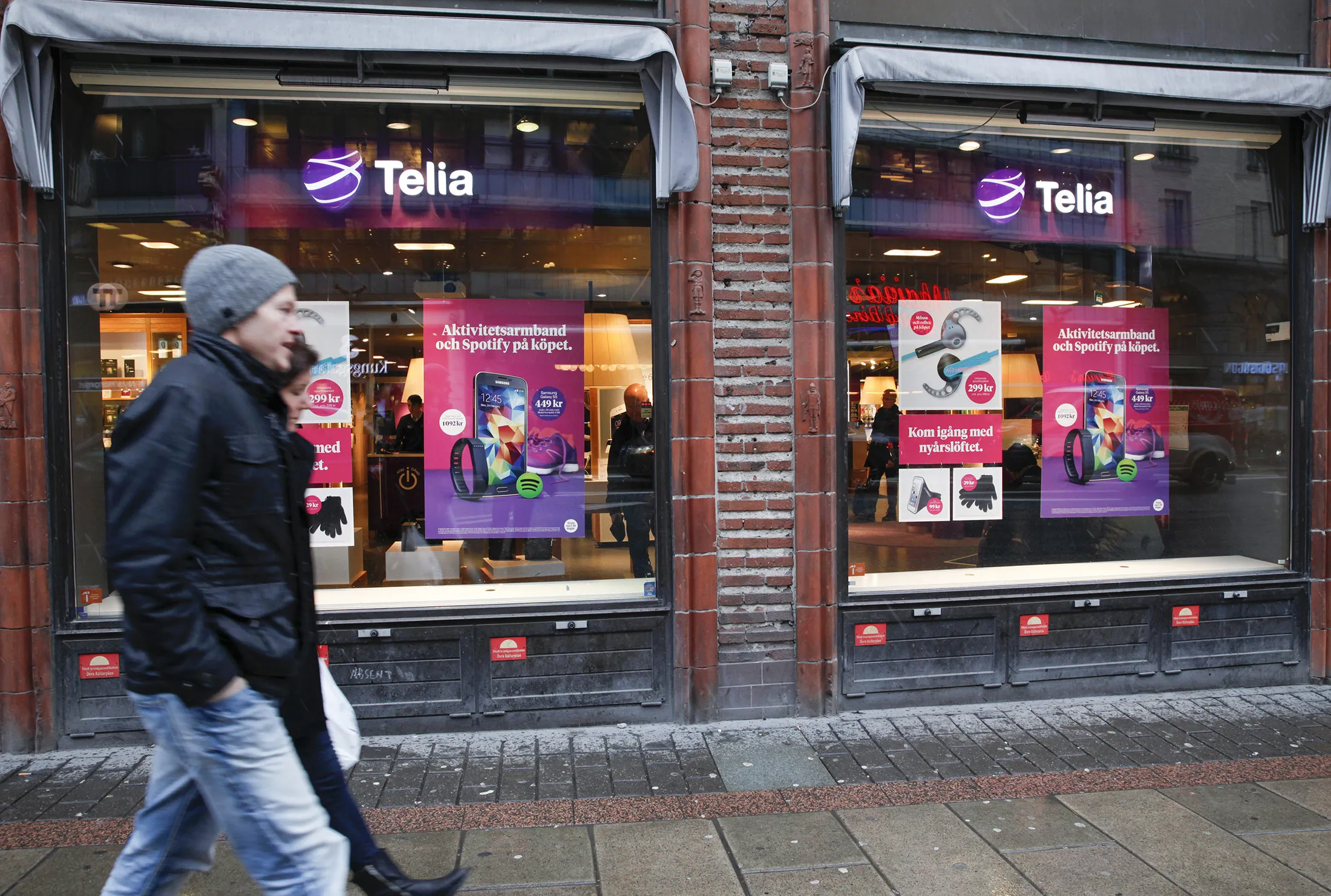 Pedestrians pass advertisements for smartphones in the windows of a Telia mobile communications store, operated by TeliaSonera AB, in Stockholm, Sweden, on Thursday, Jan. 29, 2015. TeliaSonera AB reported earnings that missed analysts' estimates and forecast that 2015 profit won't grow as Sweden's biggest phone carrier faces widening competition in Nordic and Baltic markets and economic challenges in Eurasia.
