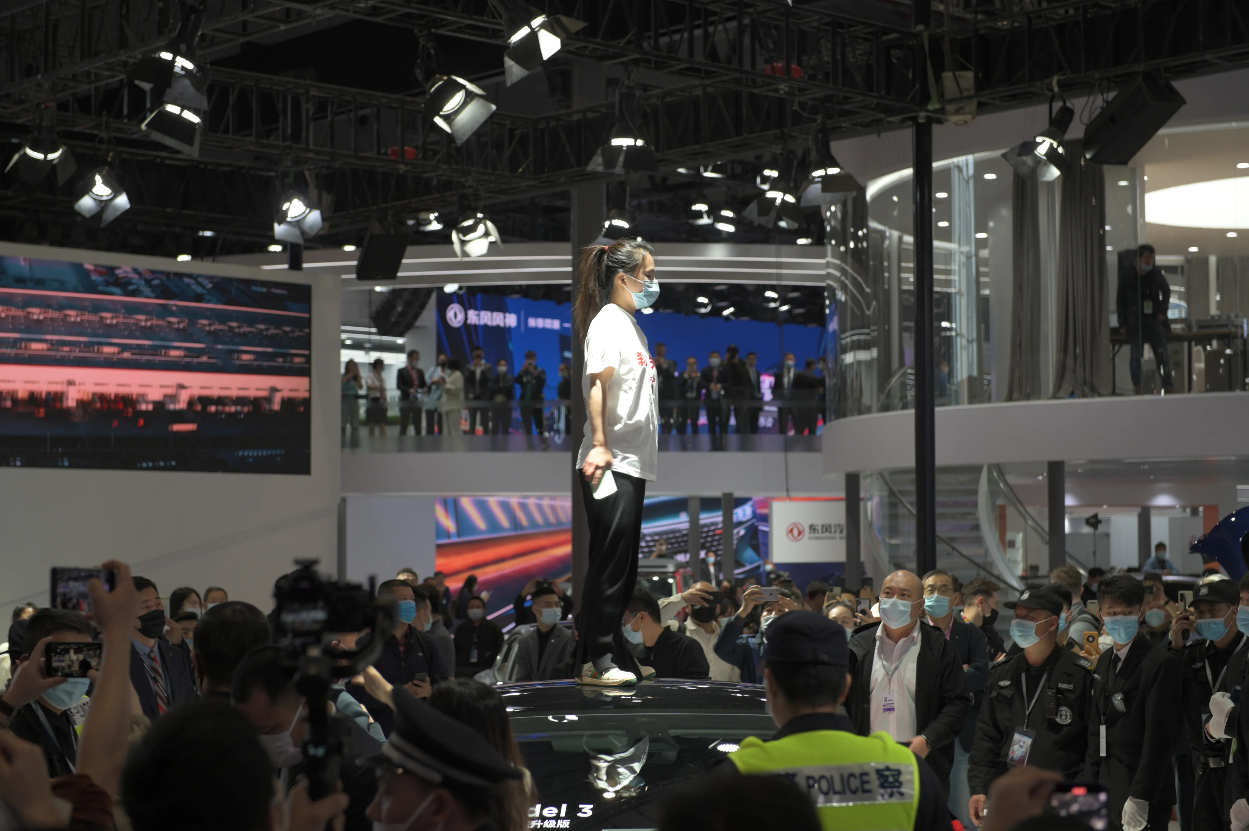 A woman stands on a Tesla 3 at the Shanghai Auto Show in 2021.