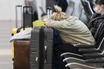 Jessica Andrijauskas, from Buenos Aires, rests her head on her luggage as she awaits the results of her COVID-19 test, at Ronald Reagan Washington National Airport, Wednesday, Dec. 29, 2021. (AP Photo/Alex Brandon)