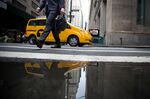 A man walks along Wall Street as a taxi turns a corner near the New York Stock Exchange (NYSE) in New York, U.S.