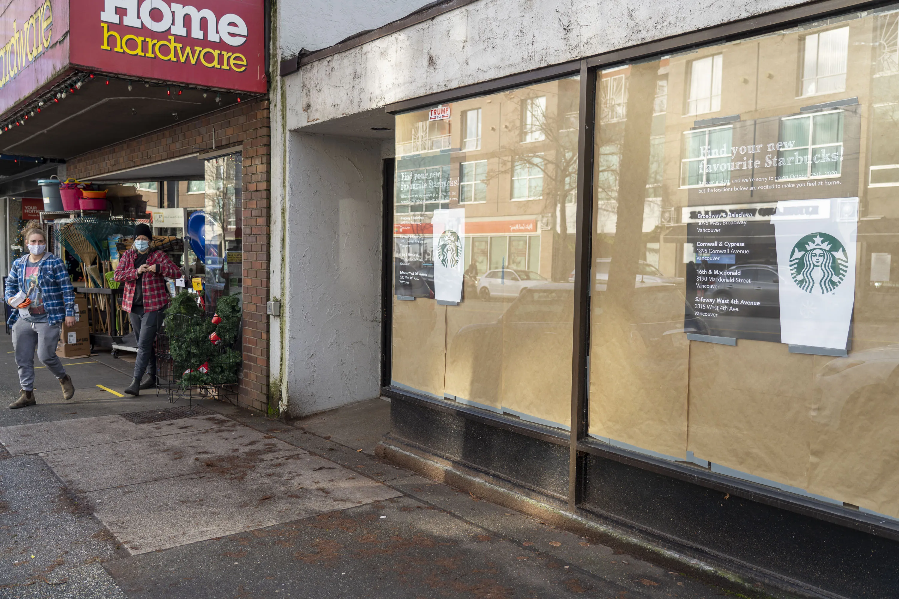Shoppers wearing protective masks exit a Vancouver hardware store next to a closed Starbucks coffee shop in November 2020.