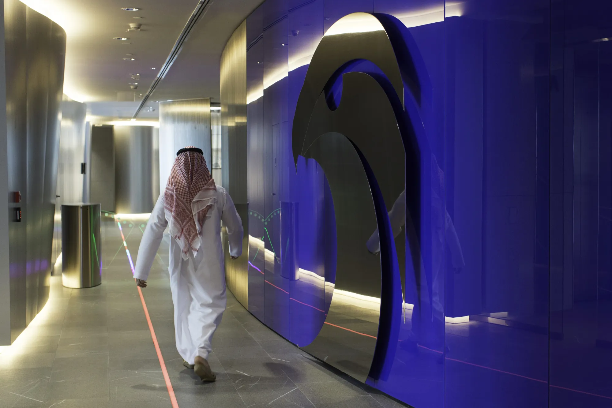 An employee passes the logo of the Abu Dhabi National Oil Company&nbsp;at the company's headquarters in Abu Dhabi, United Arab Emirates.