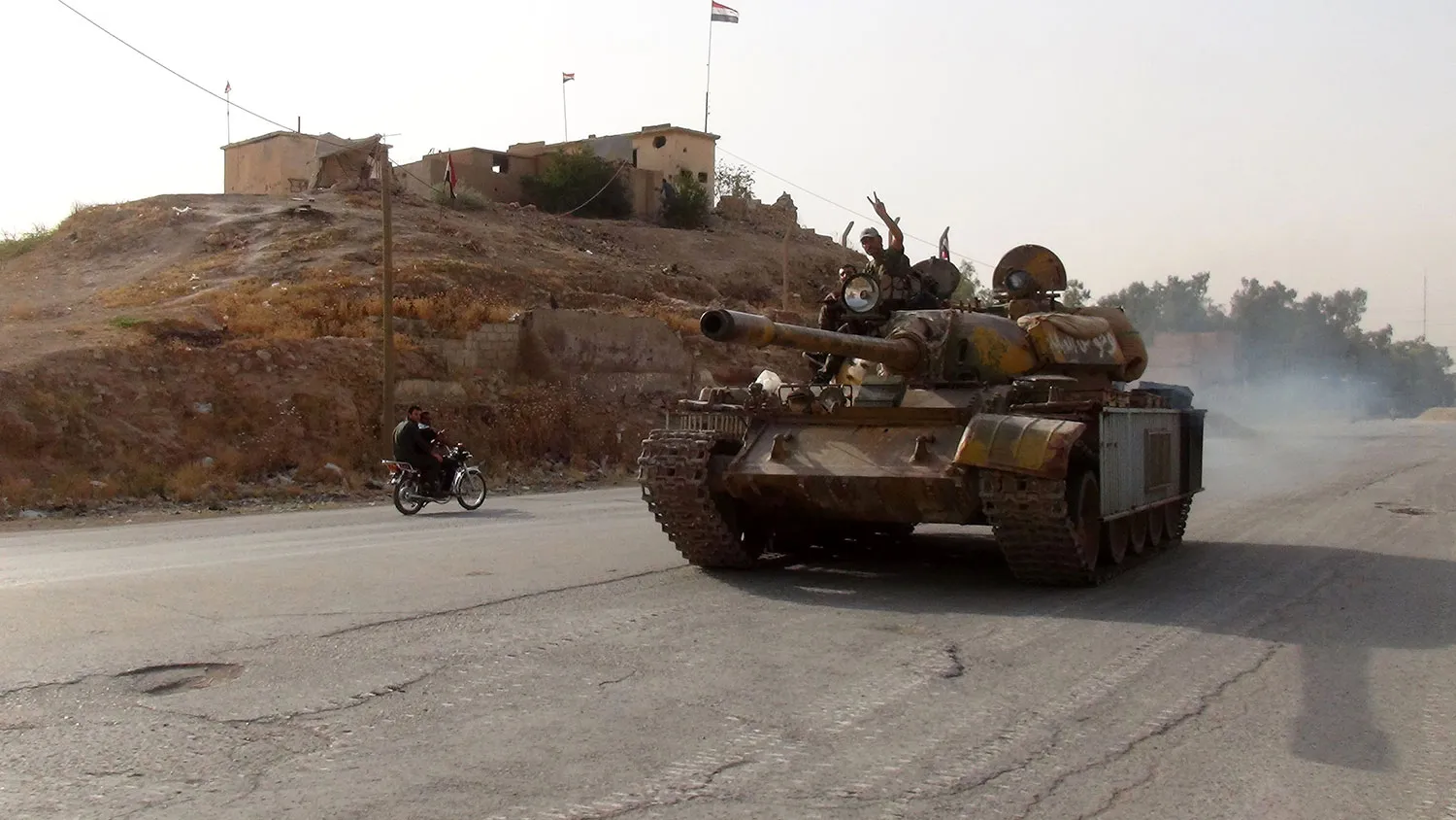 A pro-regime fighter flashes the sign of victory on Aug. 21, 2016, as he drives a tank in the southern district of Ghweiran in the Syrian northeastern city of Hasakeh, where Kurdish forces were advancing.
