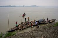 Fishermen arrive on boats to the bank of the river