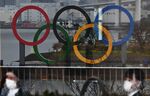 The Olympic Rings are reflected in a glass panel at Odaiba Seaside Park in Tokyo on March 8, 2020.
